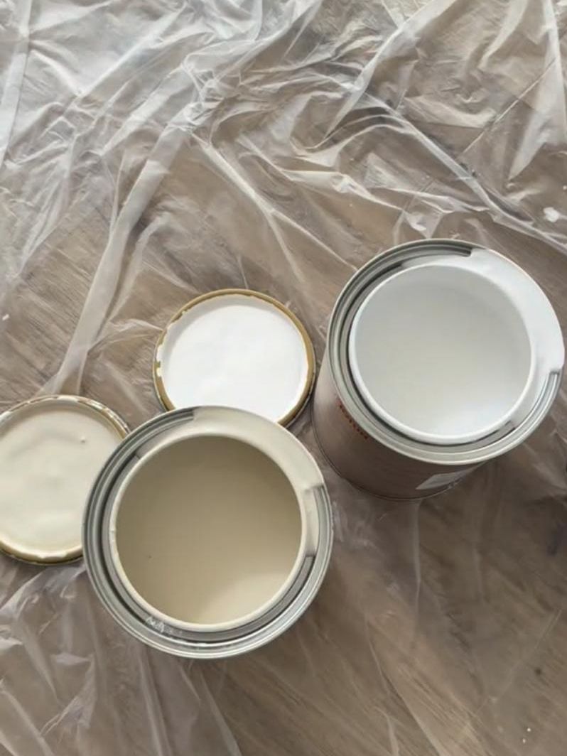 Open tins of limewash on a protected floor, mid-project